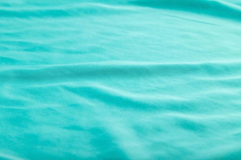 Fragment of smooth silk blue tissue. Side view, natural textile background and texture
