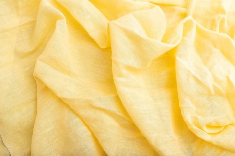 Fragment of yellow linen tissue. Top view, flat lay, natural textile background and texture. wave