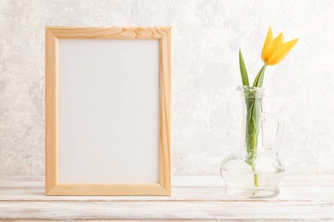 Wooden frame with orange tulip flower in glass on gray concrete background. side view, copy space,