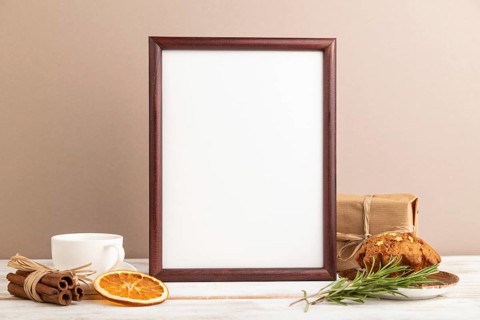 Brown wooden frame mockup with cup of coffee and cake on brown background. Blank, side view, still