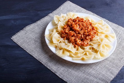 Farfalle bolognese pasta with minced meat on black wooden background. close up, copy space