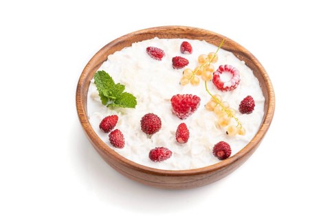 Rice flakes porridge with milk and strawberry in wooden bowl isolated on white background. Side