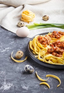 Tagliatelle bolognese pasta with minced meat on a black concrete background. side view, close up