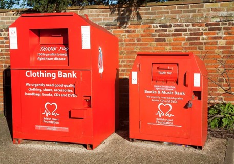 Red British Heart Foundation charity collecting containers for clothing, books and music, UK