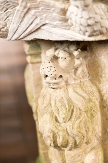 Stone carved lion animal figure support on baptismal font in village parish church, Saint John the