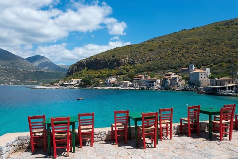 Empty red chairs on a sunny day on the shore of a calm blue sea, Limeni, Areopoli, Laconia,