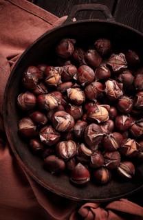 Roasted chestnuts, in an iron pan, wooden table, top view, no people, rustic style