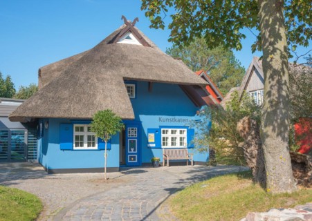A picturesque, blue-painted thatched roof house with bench in front of the entrance, open door,