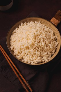 A plate of boiled rice, with wooden sticks, on a brown background, no people, selective focus,