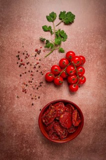 Dried tomatoes, in a bowl, top view, on a brown background