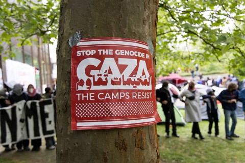 Poster Stop the genocide in Gaza / The camps resist on a tree in front of a human chain at the