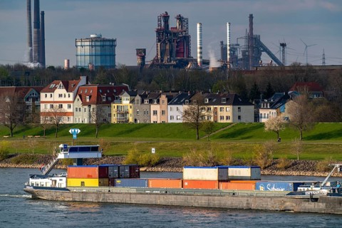 Cargo ships on the Rhine near Duisburg-Laar, houses on Deichstrasse, industrial backdrop of the