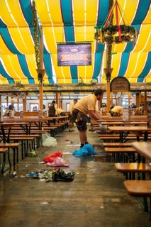 Employees cleaning the marquee after an event, rubbish scattered on the floor, Canstatter Wasen,