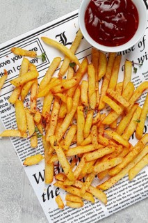 Fried French fries, scattered on a newspaper, with red sauce, top view, no people