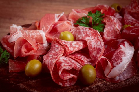 Assortment, sliced meat appetizer, prosciutto, salami and ham, with olives, on a wooden board,