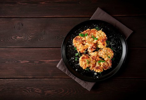 Steak, cauliflower, with cheese, spices, homemade, on a wooden table, dark background, close-up,