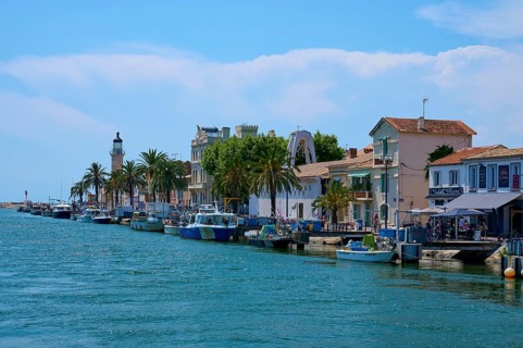 Coastal town with colourful houses, boats in the water and a lighthouse in the background on a