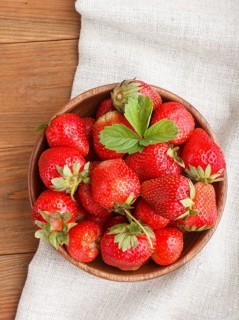 Fresh red strawberry in wooden bowl on wooden background. top view, flat lay, close up