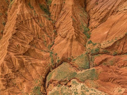 Eroded mountain landscape, top-down, canyon with red and orange rock formations, aerial view,