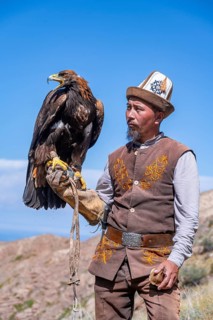 Traditional Kyrgyz eagle hunter with eagle in the mountains, near Kysyl-Suu, Kyrgyzstan, Asia