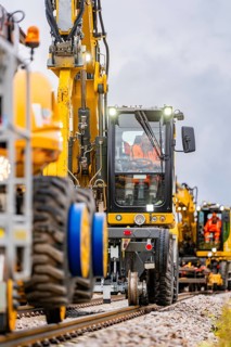 Vehicles and workers working closely together on a railway line with machines, track construction