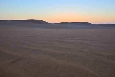 Vast desert landscape at sunset with gentle sand dunes and minimalist atmosphere, Matruh, Great