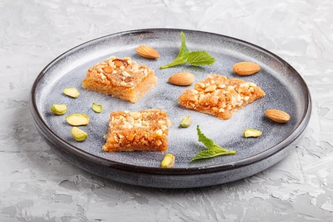 Traditional arabic sweets in gray ceramic plate on a gray concrete background. side view, close up