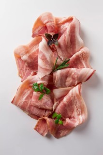 Raw bacon, sliced, with micro greenery and spices, on a white background, close-up