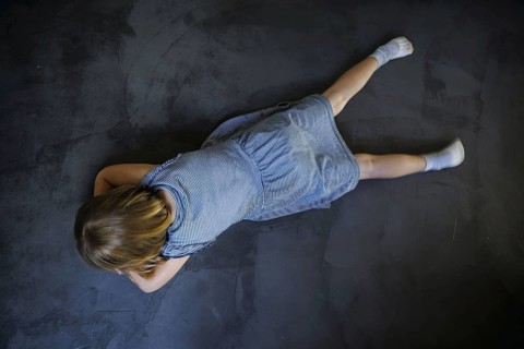 Symbol photo on the subject of tantrums (posed scene) . A little girl lies on the floor and is sad.