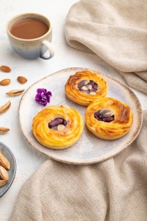 Small cheesecakes with jam and almonds with cup of coffee on a white concrete background and linen