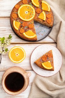 Orange cake and a cup of coffee on a white wooden background and linen textile. Top view, flat lay,