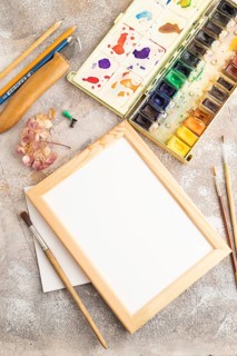 Drawing accessories set: brushes, pencils, watercolor, frame on brown concrete background. Top