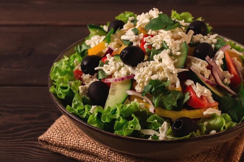 Traditional Bulgarian dish, Shopska salad, on a wooden table, salad of fresh vegetables, top view,