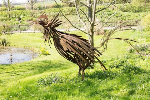 Iron cockerel sculpture, pond, wildflowers in garden of Manor Farm, Huish, Vale of Pewsey,
