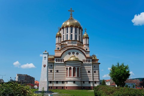 Church with golden domes against a clear sky, embedded in urban greenery, Orthodox Cathedral of St