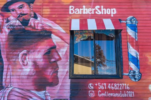 Colourful graffito, street art on the facade of a hairdresser and barber shop, city of Punta