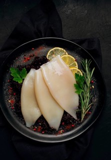 Fresh body, squid, raw, three carcasses, top view, no people, on a plate