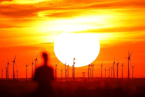 Joggers on Berlin's Drachenberg at sunset. A wind farm near Nauen in Brandenburg can be seen in the