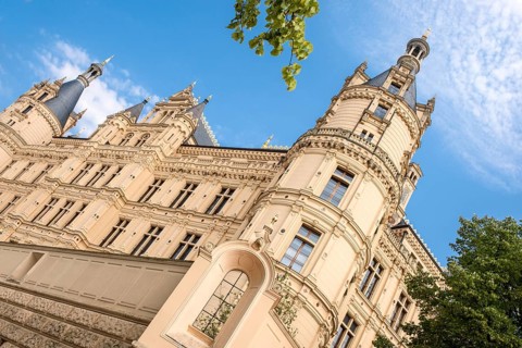Schwerin Castle on a sunny day in summer with blue sky and white clouds, castle lake facade, in the