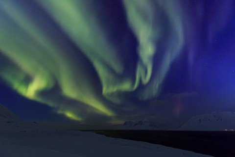 Yellow and green northern lights over snowy mountains, fjord, aurora borealis, winter,