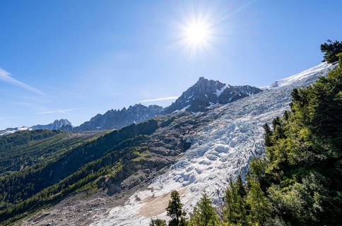 View of glacier Glacier des Bossons with sun star, behind summit of Aiguille du Midi, Chamonix,