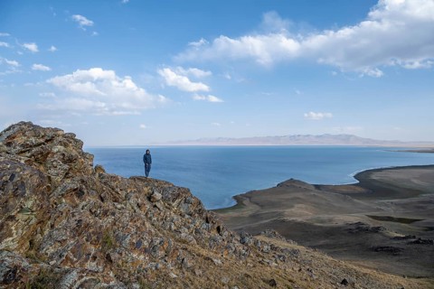 Tourist standing on a hill, view of mountain lake Song Kul, Naryn region, Kyrgyzstan, Asia