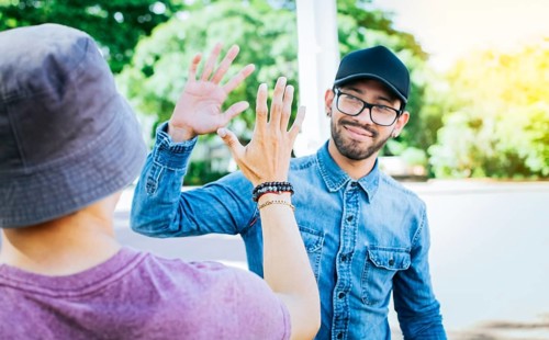 Two smiling friends shaking hands on the street. Friends shaking hands outdoors. Concept of two