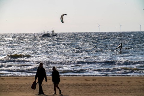 Kitesurfers and shrimp boats off the coast of Scheveningen, walkers on the beach, The Hague,