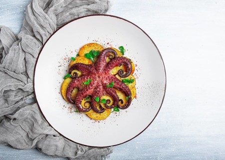 Octopus with potatoes and spices, on a light plate, top view, no people, homemade, close-up