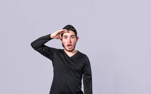 Amazed young man with his mouth open with his hand on his forehead, surprised guy with his mouth