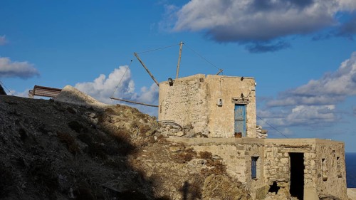 Abandoned mill ruins on a hill under a blue sky with clouds, historical, Colourful mountain
