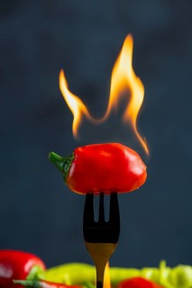 Burning red pepperoni on a fork, close-up, food photography