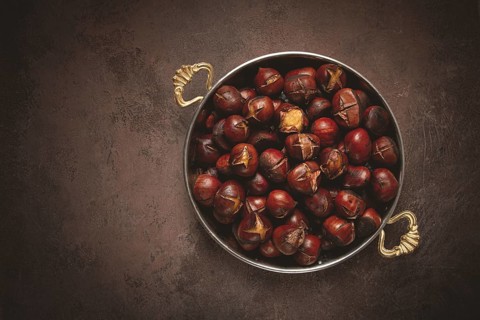 Roasted chestnuts, in a wooden plate, top view, homemade, no people