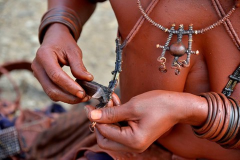 Himba woman cleaning her traditional jewellery, Opuwo, Kaokoland, Kunene, Namibia, Africa